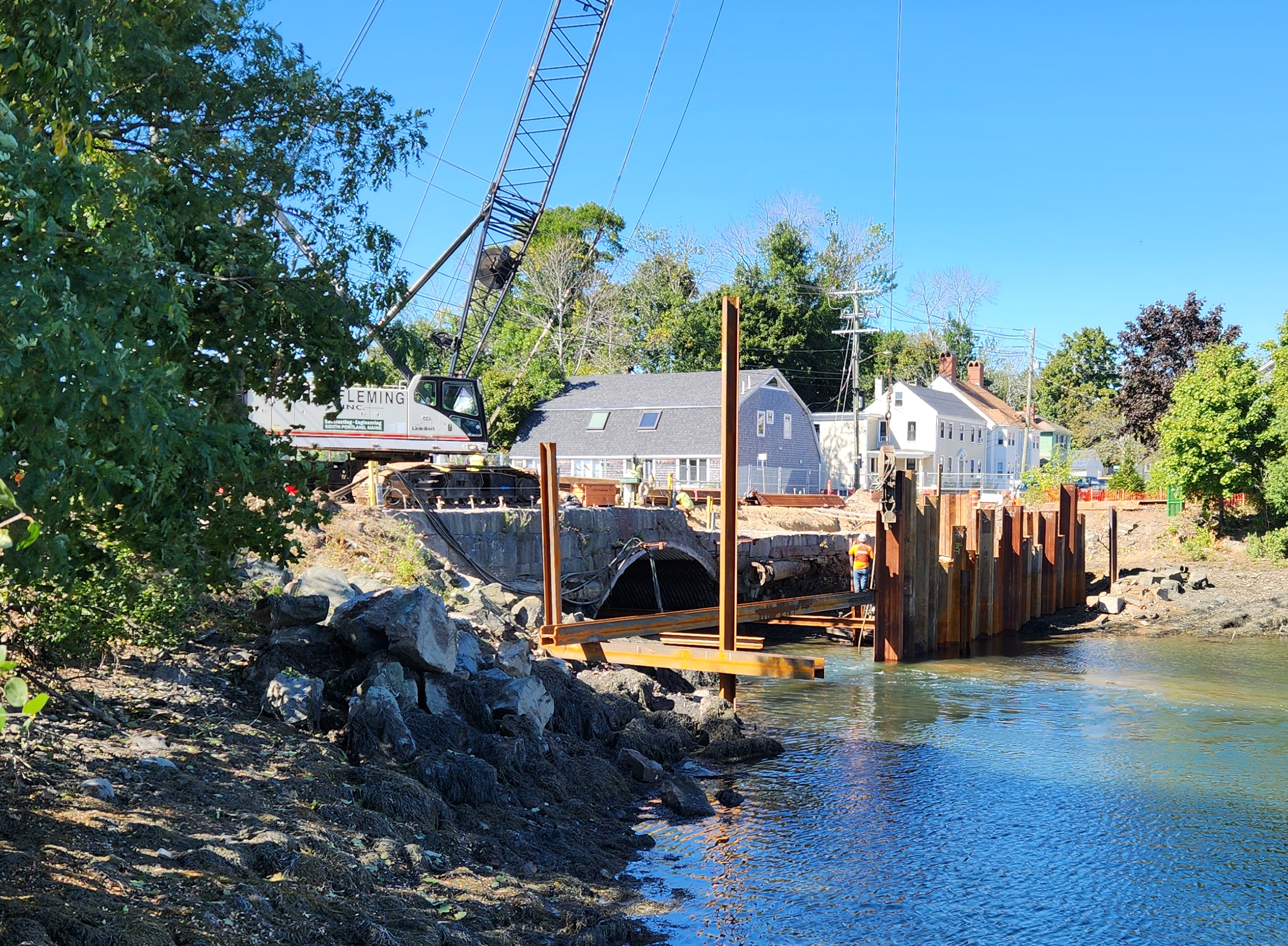 Image shows the Maplewood Avenue Bridge from the shore with a crane installing the coffer dam